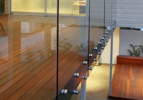Glazen balustrade met zichtbare puntbevestigingen langs een houten terras