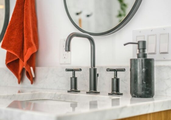 Badkamer met donker metalen kraan, grepen en zeepdispenser