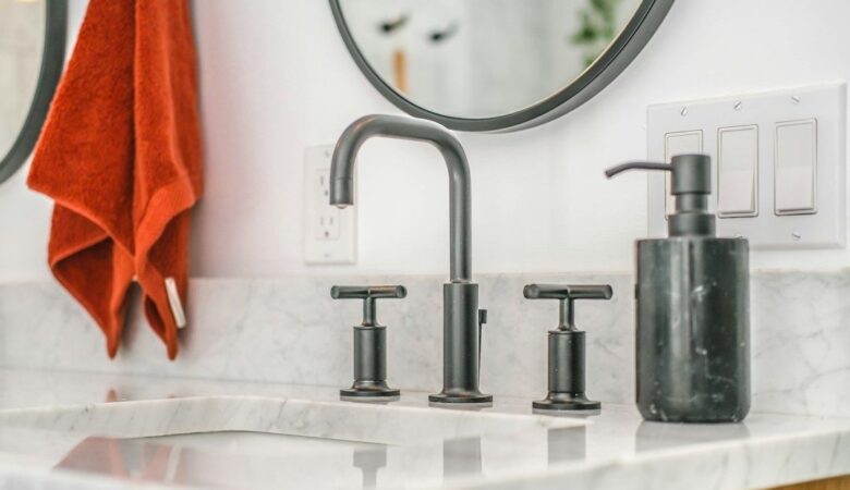 Badkamer met donker metalen kraan, grepen en zeepdispenser