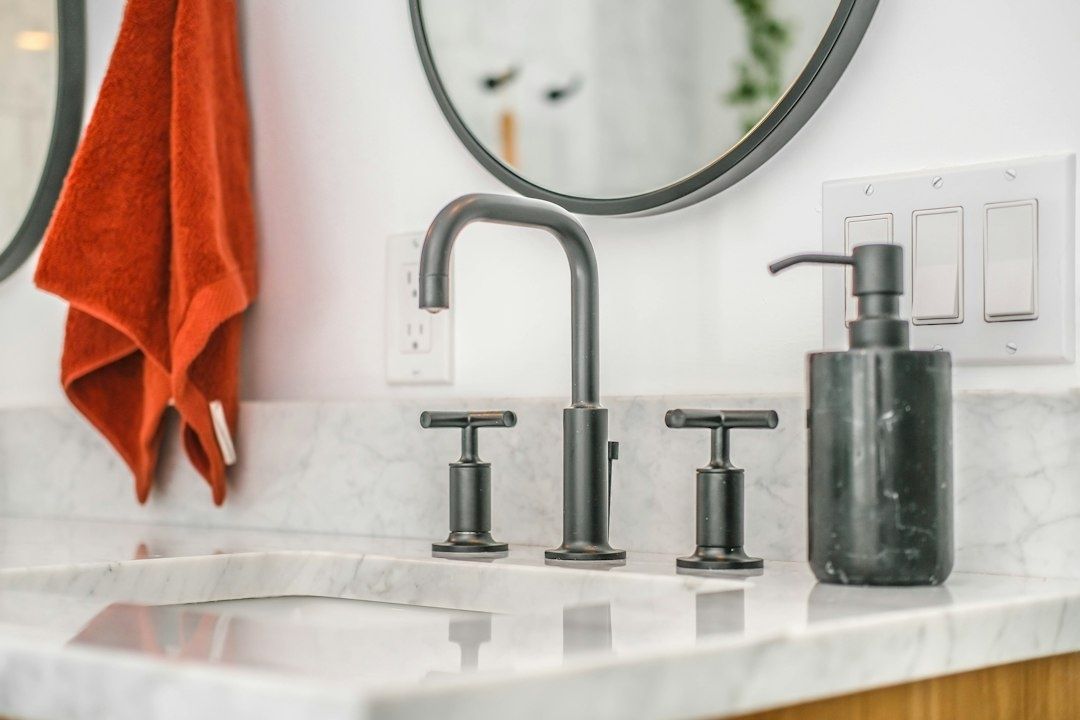 Badkamer met donker metalen kraan, grepen en zeepdispenser